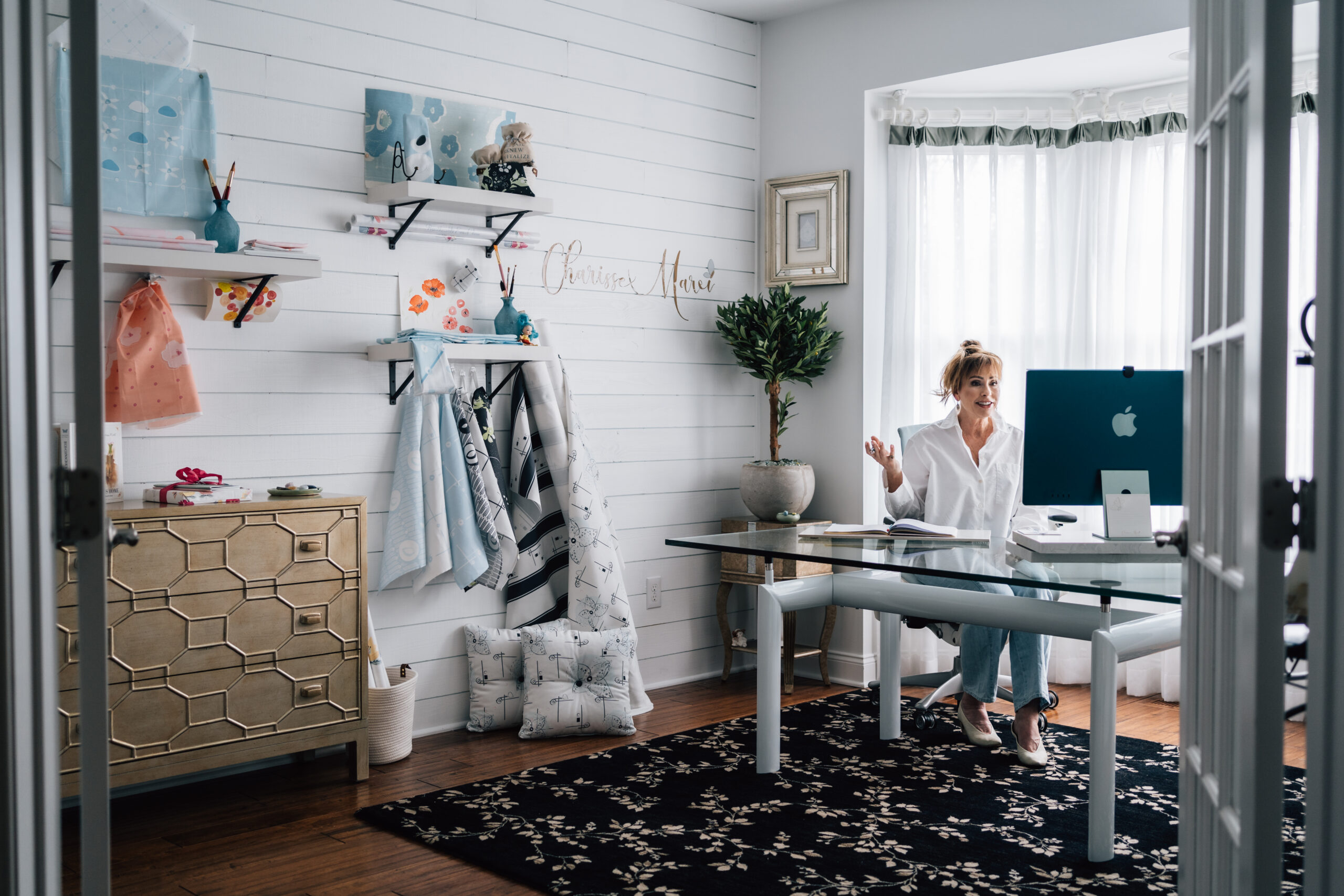 Charisse Marei working at her desk in a bright home office and design studio, surrounded by creative tools, books, and inspiring décor.